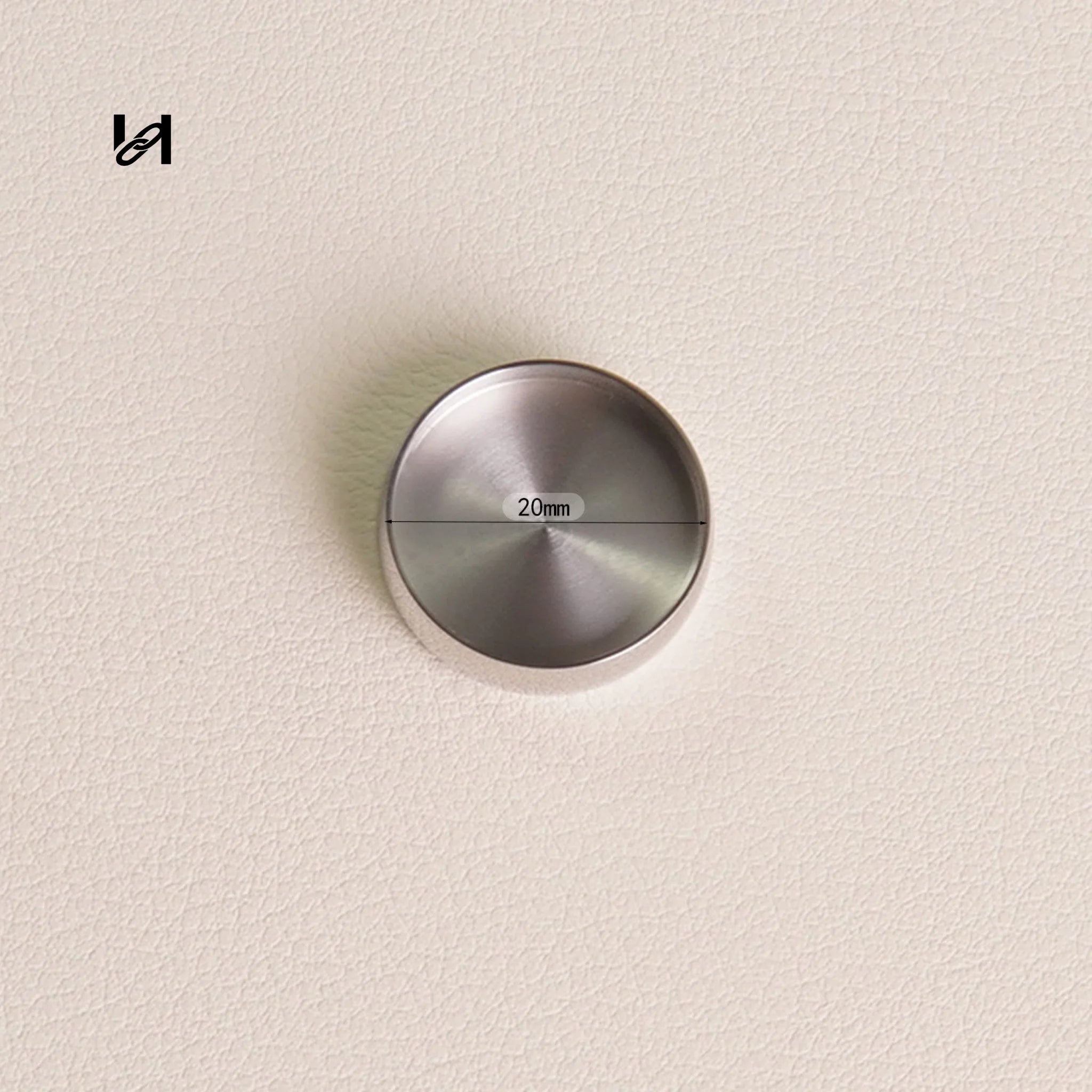 Metallic round object with '20mm' marking on a beige background